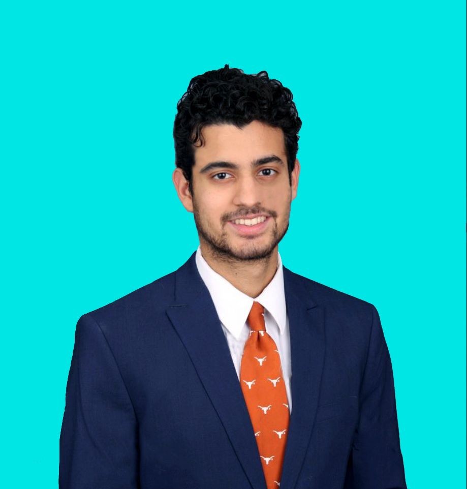 Man in a blue suit with a white shirt and orange tie, smiling against a turquoise background.