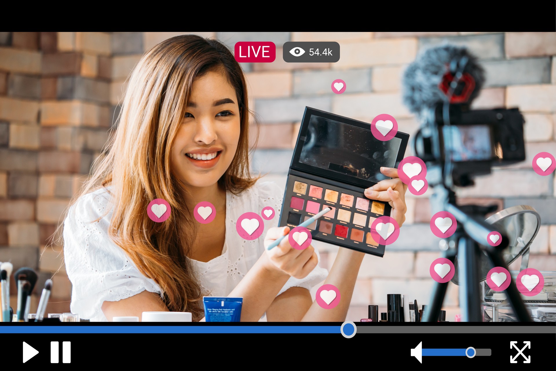 Woman does makeup while recording live stream with video player interface