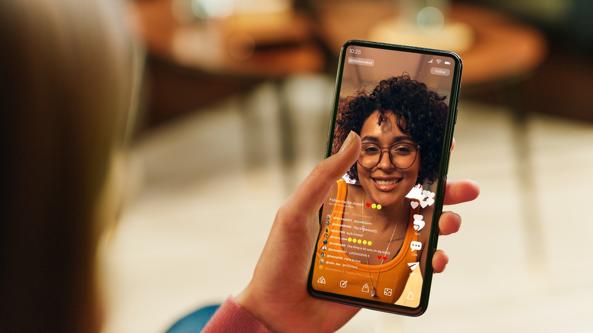 Feminine Hand Holding a Smartphone with Social Media Application on Display. Female in Casual Clothes Resting at Home and Watching Videos on Mobile Device. Close Up Over the Shoulder Photo.